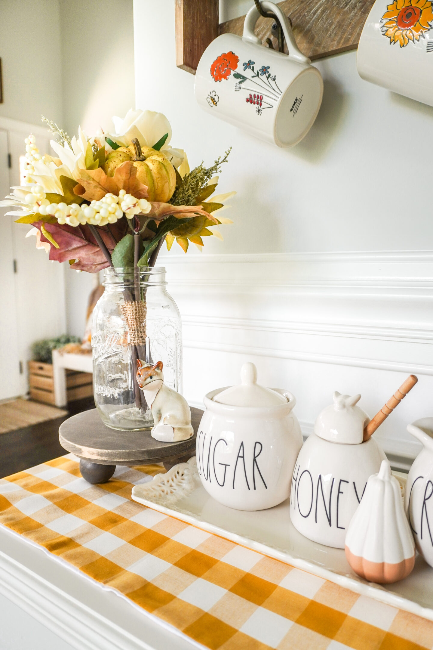 fall bouquet inside of a vintage mason jar with a small fox on the pedestal beside it